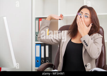 Junge langweilig Geschäftsfrau am Tisch mit Laptop sitzen und schlafen wollen, während Gähnen am Arbeitsplatz in modernen Büro. Stockfoto