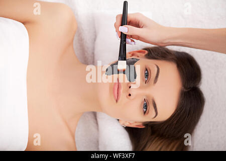 Hardware Kosmetologie. Closeup Bild der reizende junge Frau mit Creme Maske in einem Schönheitssalon. Stockfoto