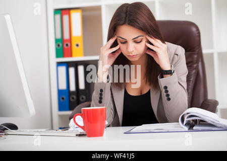 Kopfschmerzen und Stress bei der Arbeit. Porträt der jungen Geschäftsfrau in Ihrem Büro Stockfoto