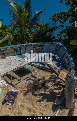 Aufgegeben und gebrochene Holz blau Boot am Strand liegt mit viel Sand, Zeichen und abgestorbene Pflanzen, Bohrungen auf dem Deck und dem Hintergrund der pa Stockfoto