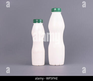 Weißer Kunststoff Flasche mit Milch, Joghurt oder Kefir, auf grauem Hintergrund. Mock up Template Design ohne Etikett. Stockfoto
