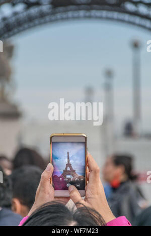 Neugierig und interessantes Bild eines Bildes in einem Bild der Tourist, der eine nach oben Foto des Eiffelturm in einem gemeinsamen Smartphone mit Stockfoto