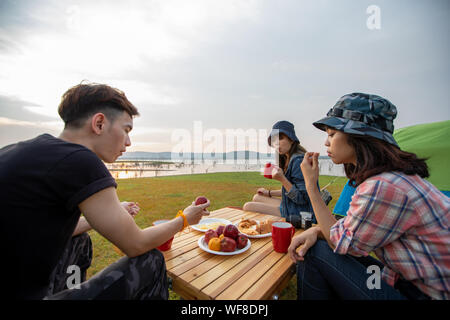 Eine Gruppe von asiatischen Freunden trinken Kaffee und Zeit machen ein Picknick in den Sommerferien Sie sind glücklich und viel Spaß im Urlaub. Stockfoto