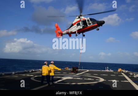 Einem MH-65 Dolphin Helikopter entlastet das Flight Deck der Coast Guard Cutter Stratton (WMSL 752) als fähnriche Olivia Calabro und Alexander Kearney, Landung signal Offiziere geben Hand Signale an das Flugpersonal Aug.28, 2019, während die Stratton die Bucht von Bengalen Transite. Die Operation war Teil der Ausbildung und Qualifikation Erfahrung für Besatzungsmitglieder von Stratton. (U.S. Coast Guard Foto von Petty Officer 1st Class Levi lesen) Stockfoto