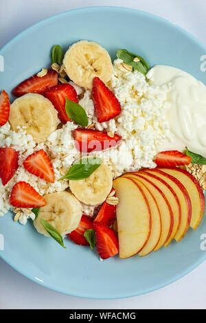 Das gesunde Essen Dessert mit Hüttenkäse und Erdbeeren in einem blauen Platte auf einer weißen Tischdecke Stockfoto