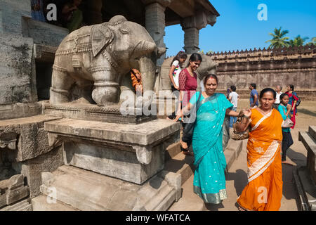 Besucher verlassen den Tempel der tausend Säulen (Saavira Kambada Basadi), einen Jain-Tempel in Moodabidri, Karnataka, Indien, und passieren Elefantensteinfiguren Stockfoto