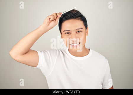 Portrait von lächelnden Mann in t-shrit seine Haare kämmen. Stockfoto