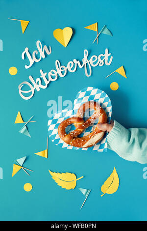 Papier Text "Ich Oktoberfest' in deutscher Sprache liebe, flach auf Papier Hintergrund mit brezel auf Papier Platte legen, dekorative Herzen, Flaggen und Blätter im Herbst. Stockfoto