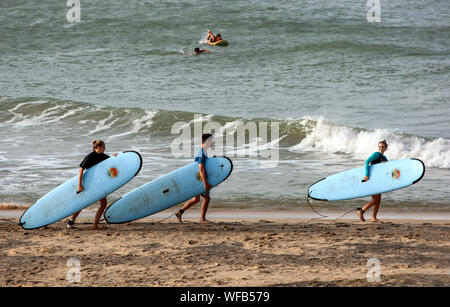 Ausländische Surfer tragen ihre surfbretter am Strand entlang Neben Elephant Rock in Arugam Bay in Sri Lanka. Stockfoto