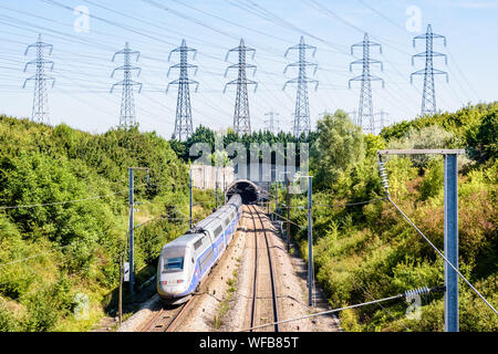 Ein doppeldecker TGV Duplex Hochgeschwindigkeitszug in Atlantik livery ist in einen Tunnel unter einer Reihe von Sendemasten auf der LGV Atlantique Eisenbahn. Stockfoto