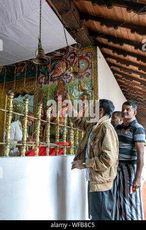 Männer Ring die Glocken am Eingang der hinduistischen Gottheit Kataragamas Schrein innerhalb der Kataragama Tempel bei Kandy in Sri Lanka. Stockfoto