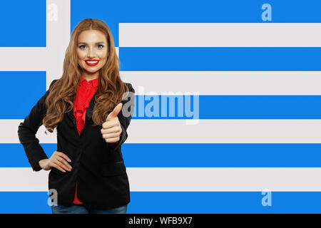 Fröhliche junge Frau Daumen oben mit Griechenland Flagge. Reise und lernen Sie die griechische Sprache Stockfoto