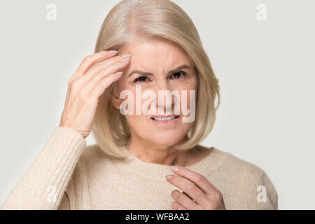 Ungesunde senior Frau isoliert in Studio Hintergrund in Migräne Stockfoto