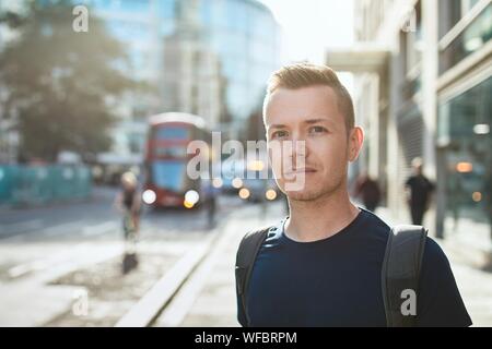 Portrait des jungen Mannes gegen Stadt Straße mit dem Bus Öffentliche Verkehrsmittel. London, Vereinigtes Königreich Stockfoto
