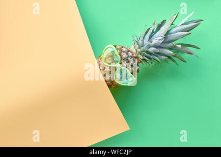 Lustige Ananas im Herzförmigen Gläser auf geometrische diagonal Papier Hintergrund in Kalk grünen und gelben Farben mit copy-Raum Stockfoto