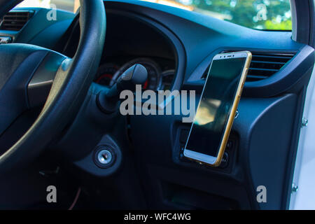 Smartphone in einem Auto für Navigieren oder GPS. Das Fahren eines Autos mit Smartphone im Halter. Handy leer, leerer Bildschirm. kopieren. Leeren Raum für Tex Stockfoto