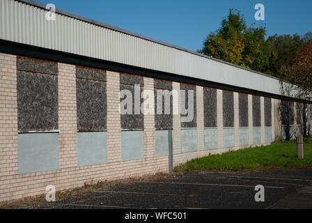 Reihe von Zugenagelten Fenstern auf einer stillgelegten Fabrik gebäude Stockfoto