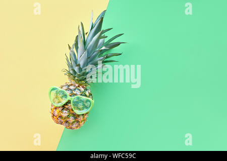 Lustige Ananas im Herzförmigen Sonnenbrille auf geometrische diagonal Neo grün und gelb Papier Hintergrund mit copy-Raum Stockfoto