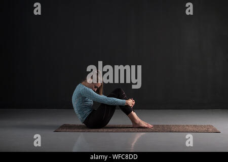 Sportliche Frau Üben Yoga, in Kind Übung sitzen, Balasana pose Variation. Hallenbad in voller Länge Stockfoto