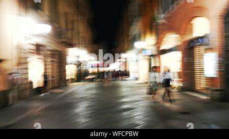 Verschwommene Bewegung von Menschen zu Fuß auf der Straße inmitten einer beleuchteten Gebäuden