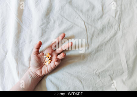 Blick von oben auf die Frau hand Selbstmord durch Überdosierung von Medikamenten. Nahaufnahme einer Überdosis Pillen und Süchtigen. Überdosierung Konzept. Stockfoto