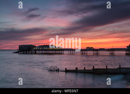 Cromer Pier in der Morgendämmerung und Sunrise mit Regenbogen Farben über den Himmel Stockfoto