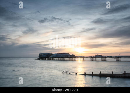 Cromer Pier in der Morgendämmerung und Sunrise mit Regenbogen Farben über den Himmel Stockfoto