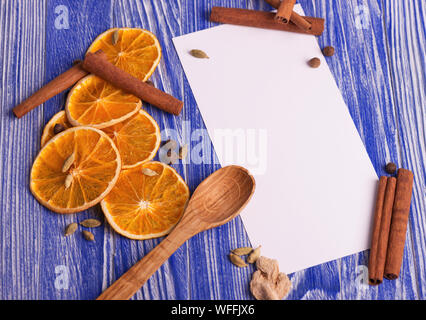 Weihnachtsdekoration. Leer für Rezepte mit getrockneten Orangenscheiben, Zimt und Gewürze auf einem blauen Hintergrund. Stockfoto