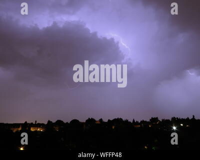 Blitz über Silhouette Stadtbild gegen Sturm Wolken bei Nacht