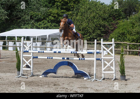 Mann und Kastanie Horse Jumping einen Zaun Stockfoto