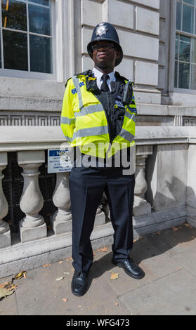 Einsame schwarze Metropolitan Police Officer außerhalb des Cabinet Office in Whitehall, Westminster, London, England, UK. Polizist in London. Stockfoto