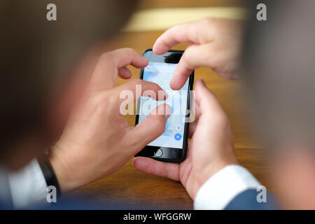 Zwei Geschäftsleute im Büro am Schreibtisch Studie Informationen auf dem Bildschirm des Smartphones Stockfoto