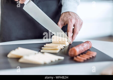 Bis zu schließen. Mann schneiden Käse Sandwiches Stockfoto