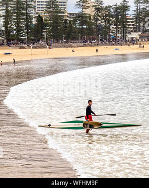 Mann in das Meer mit einem Kajak und paddeln an der Manly Beach Sydney NSW Australien. Stockfoto