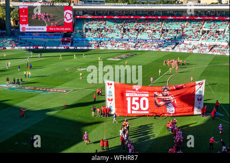 Sydney Football Club team Spieler läuft durch Banner gratulieren Dane Rampe auf dem Spielen 150 AFL Spiele, SCG Sydney NSW Australien Stockfoto