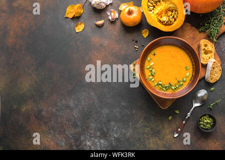 Kürbissuppe und organischen Kürbisse auf rustikalen Holztisch. Saisonale Herbst essen - Würzige Kürbissuppe mit Thymian und Kürbiskernen. Stockfoto