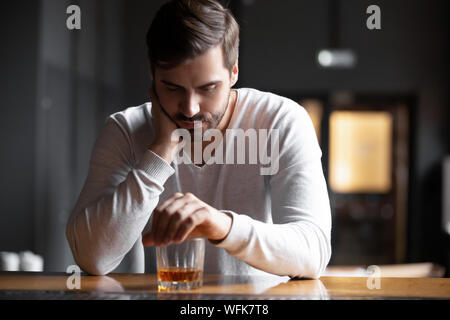 Mann trinkt alkoholische Sitzen mit Glas trinken Whisky allein umgekippt Stockfoto