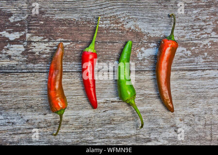 Vier peperonis liegen auf einem hölzernen Hintergrund Stockfoto
