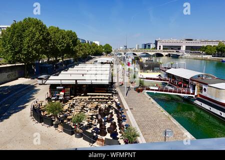 Schwimmende Bars und Restaurants mit Sitzmöglichkeiten im Freien am Flussufer im 13. Arrondissement, tagsüber im August, Paris, Frankreich Stockfoto