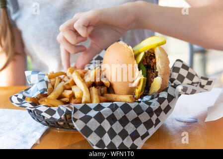 Vegan schwarze Bohnen Linsen Hamburger und Pommes frites in Papier gefüttert Warenkorb auf Restaurant Terrasse Tisch Stockfoto