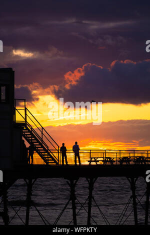 Aberystwyth Wales UK, Samstag, 31. August 2019 Leute stehen an der viktorianischen Badeort von Aberystwyth Pier sind silhouetted, als Sie den letzten Sonnenuntergang der 2019 Sommer beobachten. Morgen, am 1. September ist der erste Tag der meteorologische Herbst. Foto Keith Morris/Alamy Live Neue Stockfoto