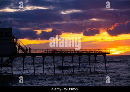 Aberystwyth Wales UK, Samstag, 31. August 2019 Leute stehen an der viktorianischen Badeort von Aberystwyth Pier sind silhouetted, als Sie den letzten Sonnenuntergang der 2019 Sommer beobachten. Morgen, am 1. September ist der erste Tag der meteorologische Herbst. Foto Keith Morris/Alamy Live Neue Stockfoto