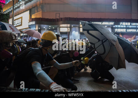 Demonstranten nehmen Deckung hinter Schirme als Polizei Tränengas und Gummigeschossen während der Demonstrationen. Gegen Polizei Aufträge, Tausende von regierungsfeindlichen Demonstranten marschierten durch die Straßen. Auseinandersetzungen mit der Polizei führte in Dutzenden von Gas Umläufe und Geschosse abgefeuert wird, schließlich zu mehreren Festnahmen. Trotz anhaltender Druck durch Demonstranten hat die Regierung von Hongkong hat noch nicht die Demonstranten zu Höhle Nachfrage nach voll ziehen der Auslieferung Rechnung. Stockfoto