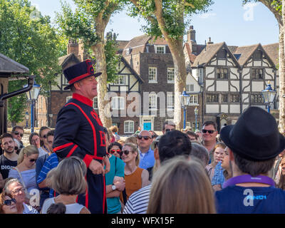 London, England - August 5, 2018: ein Yeomen Warder im Tower von London an einem warmen Sommertag, einen Vortrag vor einer Gruppe. Dieses historische Norman Castl Stockfoto