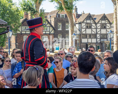 London, England - August 5, 2018: ein Yeomen Warder im Tower von London an einem warmen Sommertag, einen Vortrag vor einer Gruppe. Dieses historische Norman Castl Stockfoto