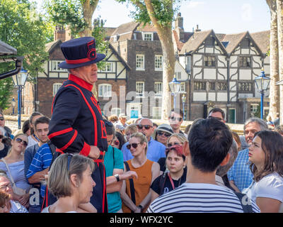 London, England - August 5, 2018: ein Yeomen Warder im Tower von London an einem warmen Sommertag, einen Vortrag vor einer Gruppe. Dieses historische Norman Castl Stockfoto