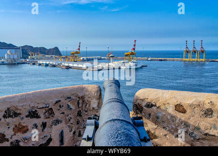 Alte Kanone auf das Fort Watch Tower auf den Hafen und das Meer mit blauer Himmel zeigt. Von Muscat, Oman. Stockfoto