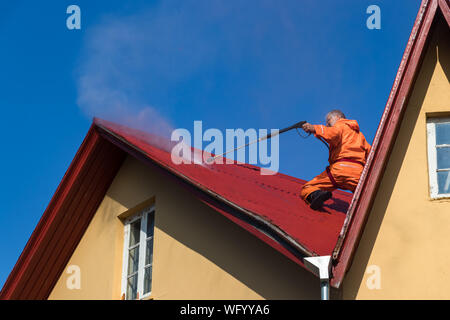 Reykjavik, Island - August 08, 2019: Ein männlicher Arbeitnehmer Reinigung ein Dach mit hohem Druck Wasser in Island. Stockfoto