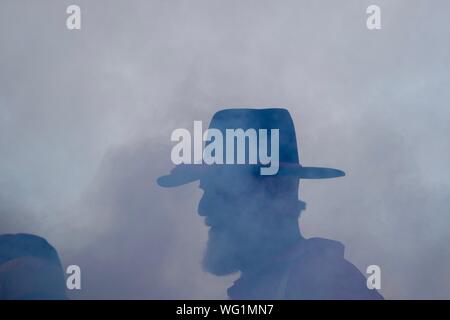 Silhouette eines Mannes im Zeitraum era Kleidung hinter einer dicken Wolke von Cannon Rauch während des Amerikanischen Bürgerkriegs reenactment gekleidet Stockfoto