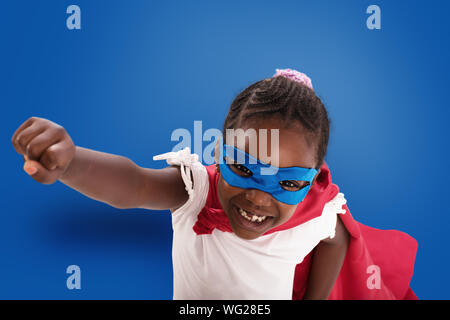 Kind wirkt wie ein Superheld der Welt auf blauem Hintergrund zu speichern. Stockfoto